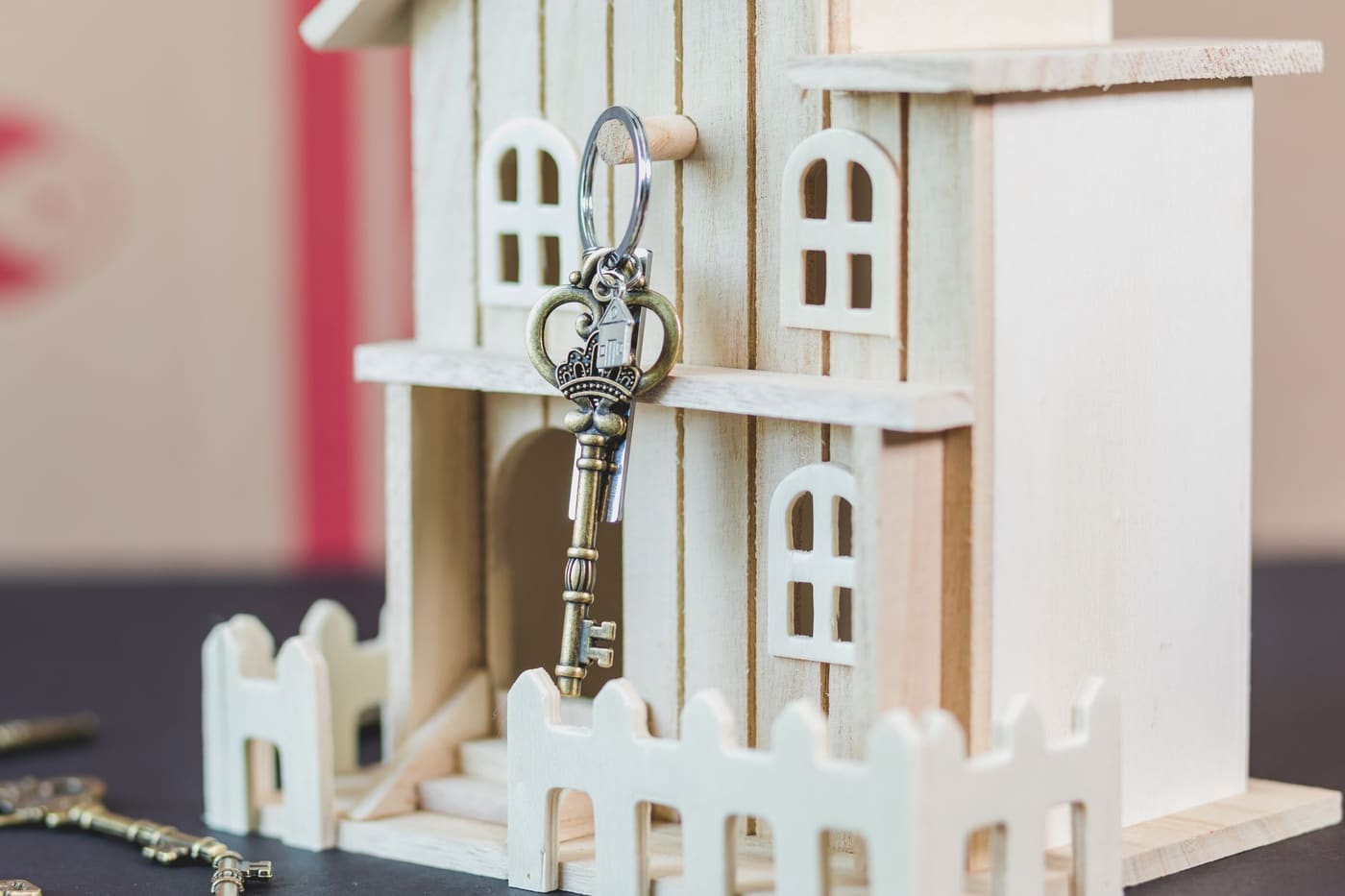 A white wooden house-shaped box with a vintage key hanging from its door